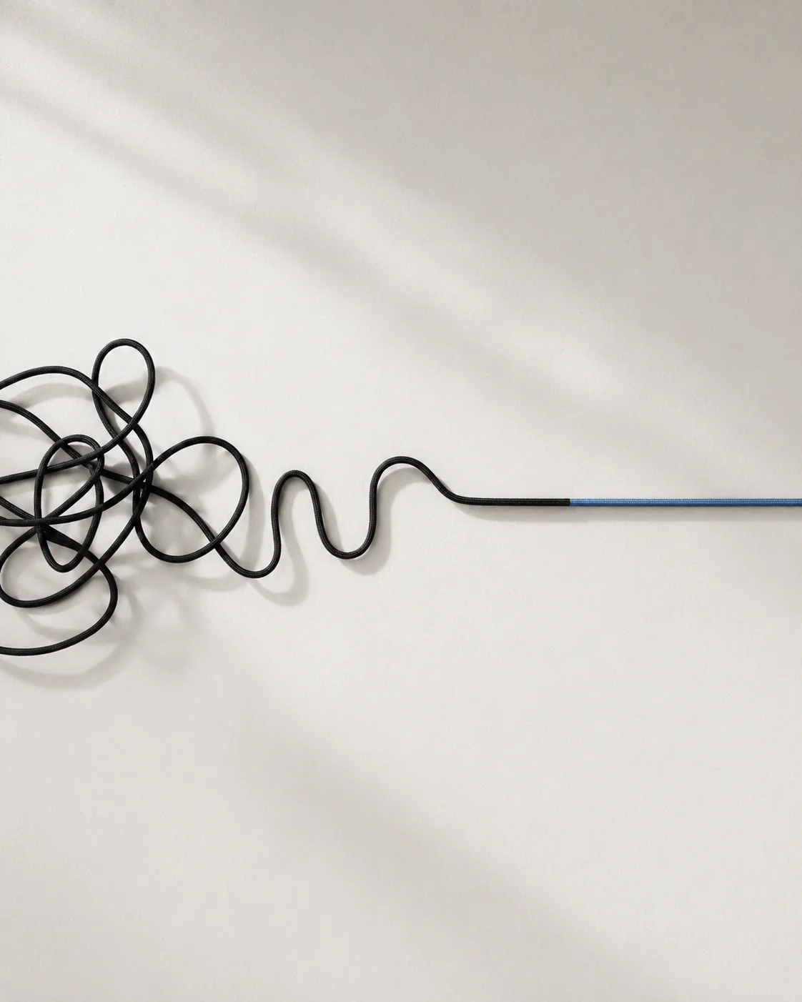 Um cordão preto embolado que se desenrola até virar uma linha azul reta, saindo pela direita.